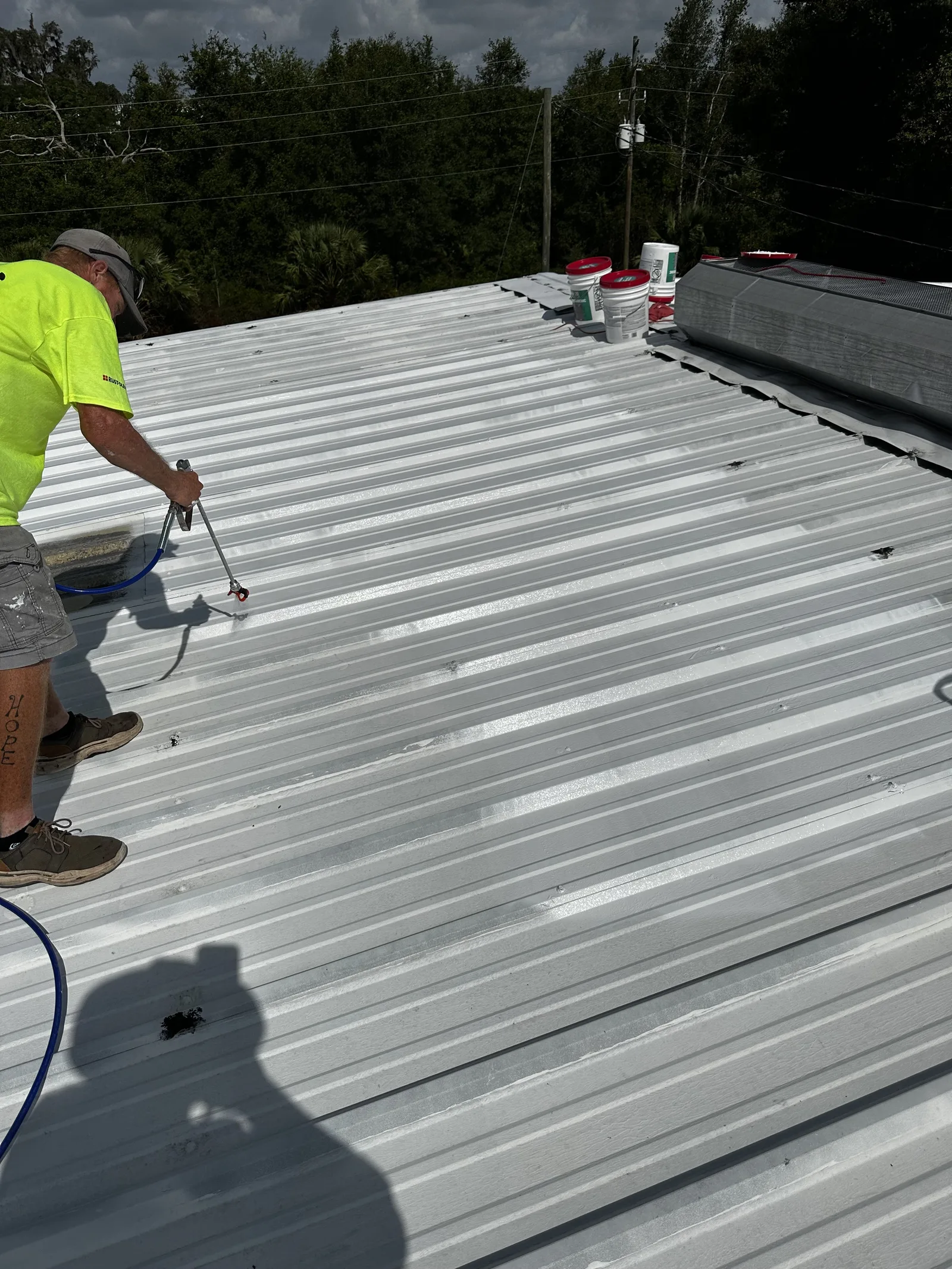 Roofer spraying white elastomeric coating across a low-slope residential roof in Salt Lake City, UT