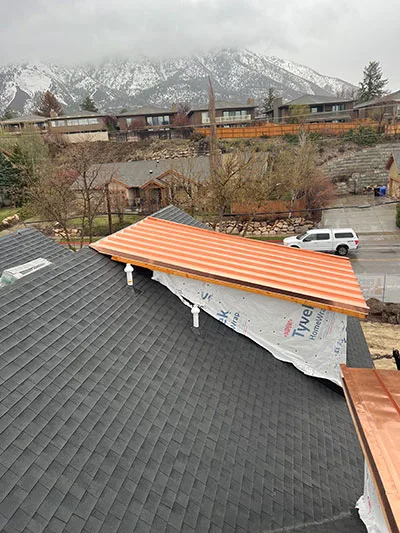 New metal roof panels going on a bench home with the snow-covered Wasatch range behind, Salt Lake City, UT