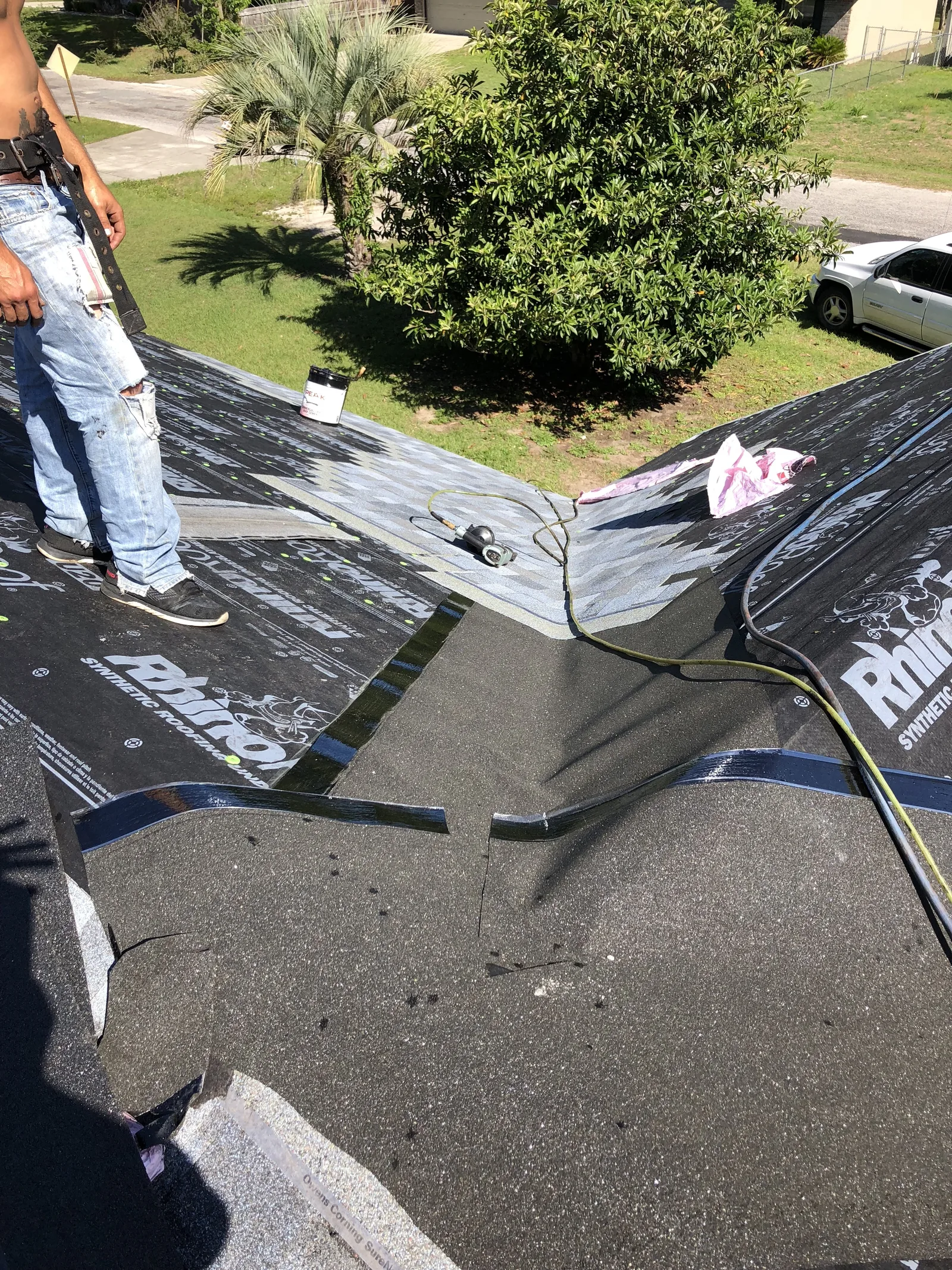 Synthetic underlayment rolled into a roof valley with a roofer's boots at the edge of frame in Millcreek, UT