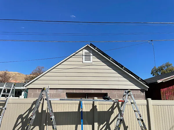 Gable end of a Salt Lake City, UT home stripped and re-sided, with ladders still set against the wall
