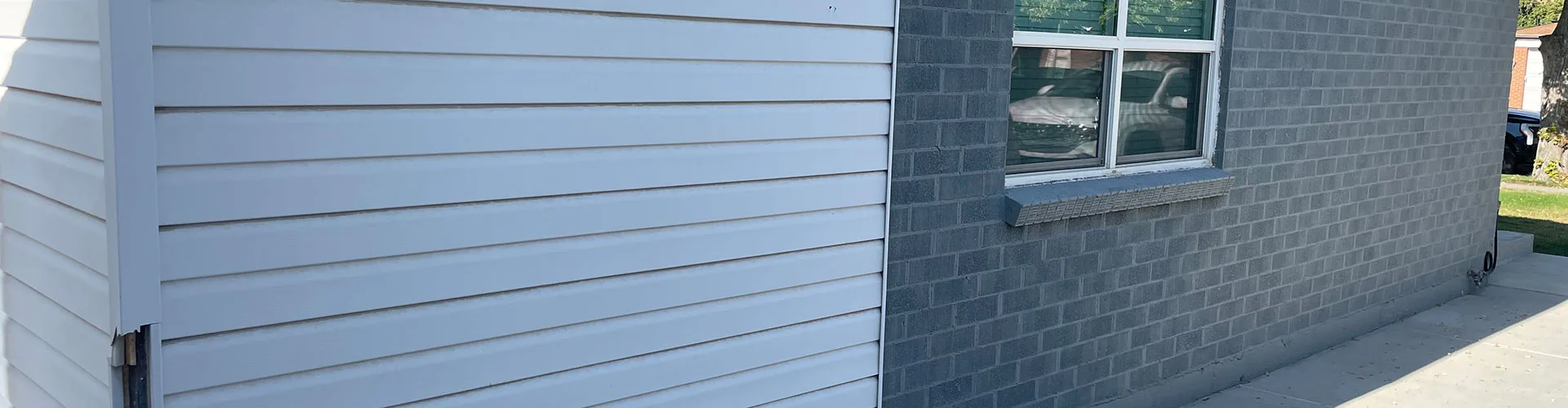 New white siding meeting the original brick on a repaired home wall in Salt Lake City, UT